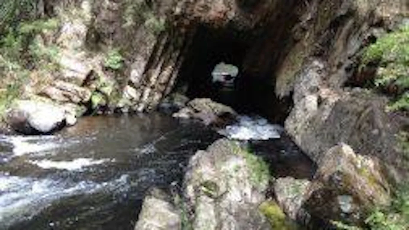 The river rushing out of a rock-cut tunnel