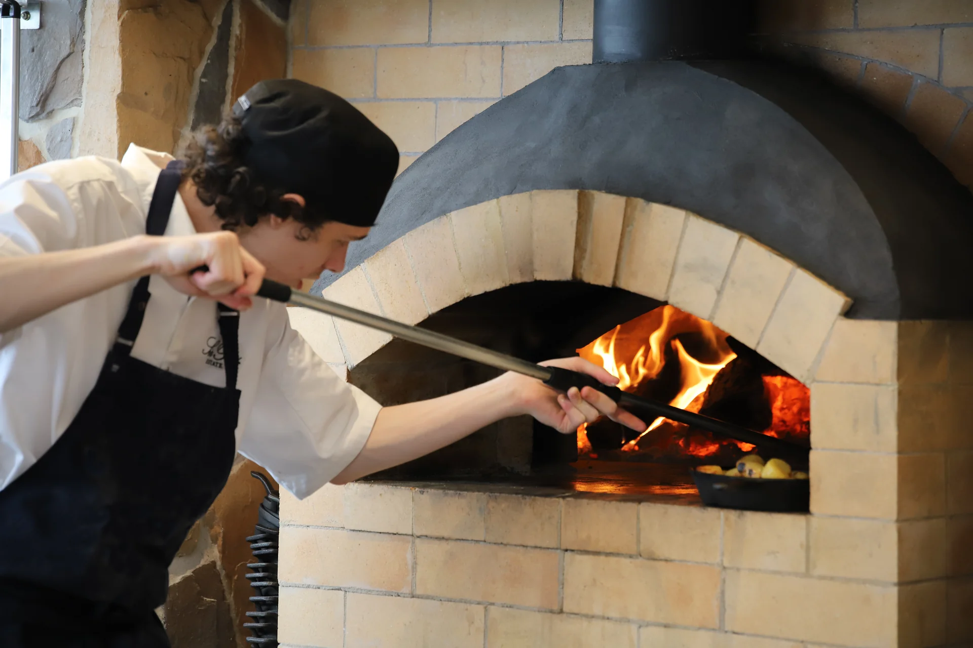 A chef sliding a pizza into a wood-fired oven