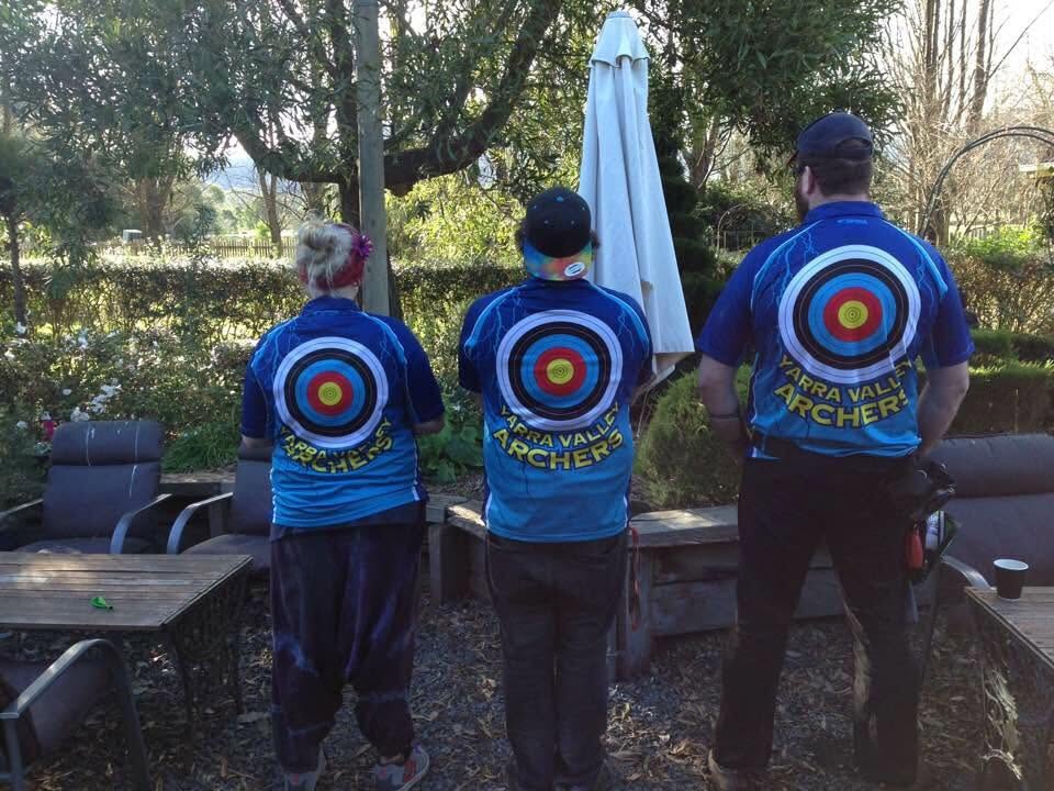 Three archers in target-printed club shirts, seen from behind