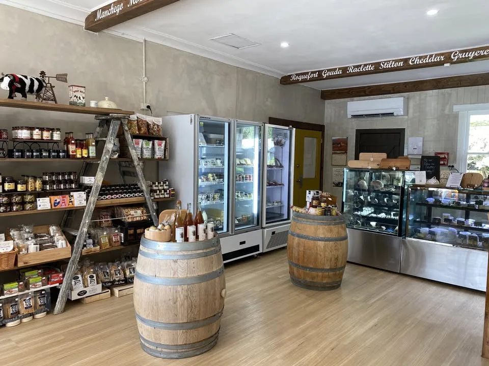 Inside a delicatessen: shelves of jars, fridges and wine barrels