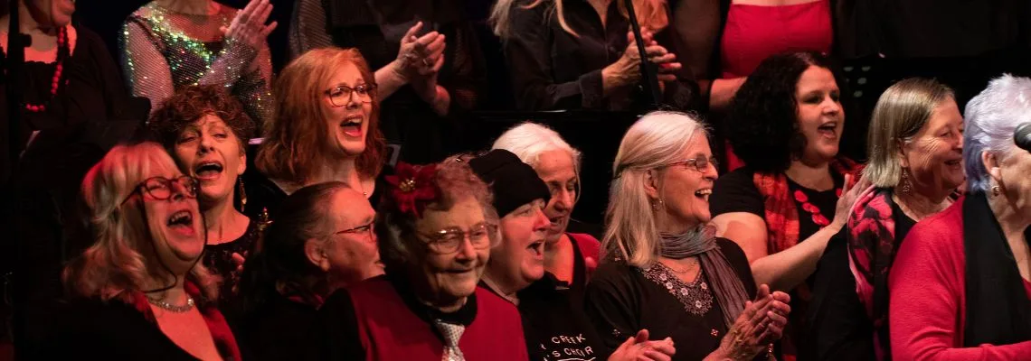 Members of the Badger Creek Women's Choir singing and clapping on stage
