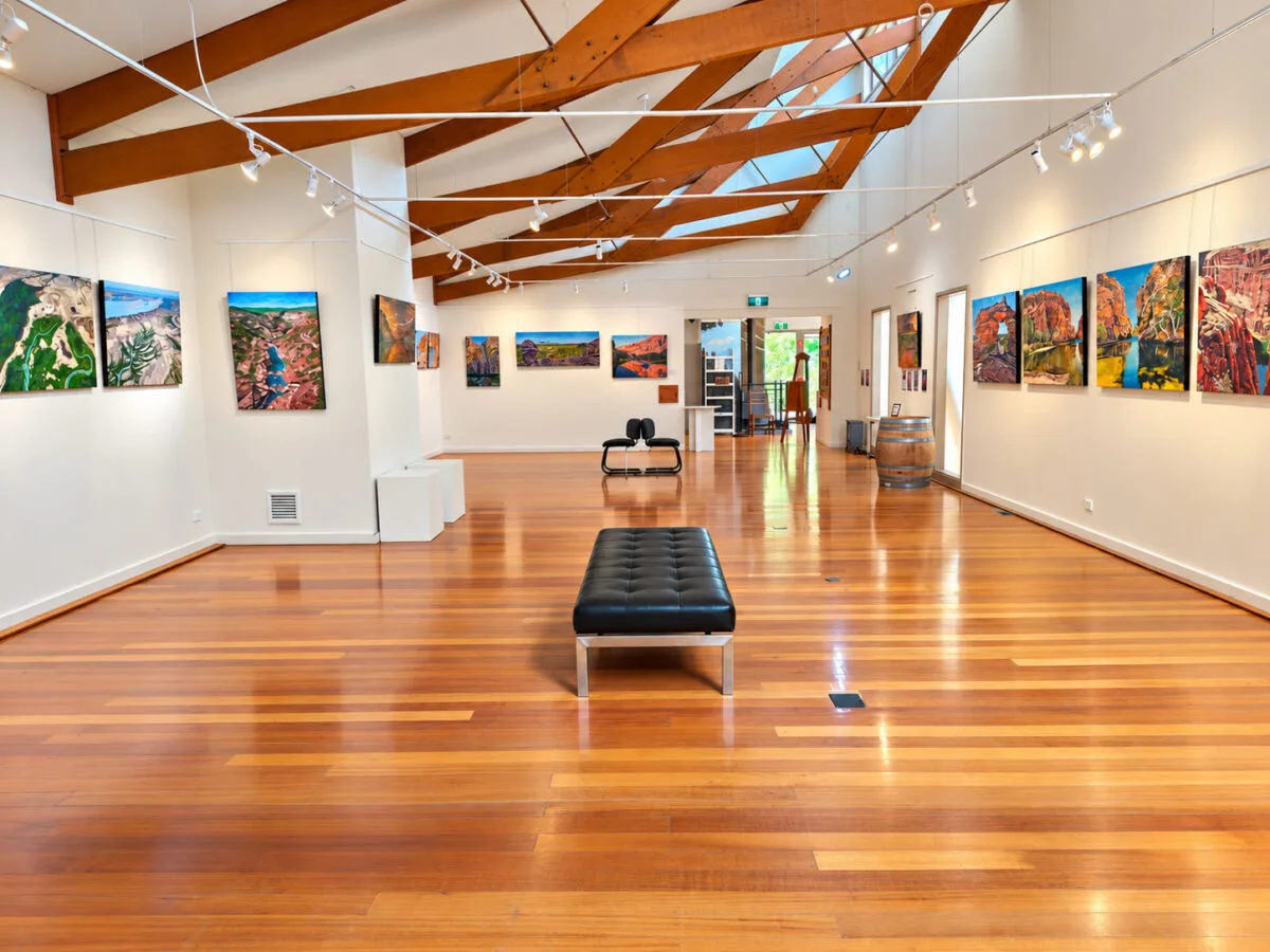 The Waterwheel gallery: landscape paintings on white walls under timber roof beams
