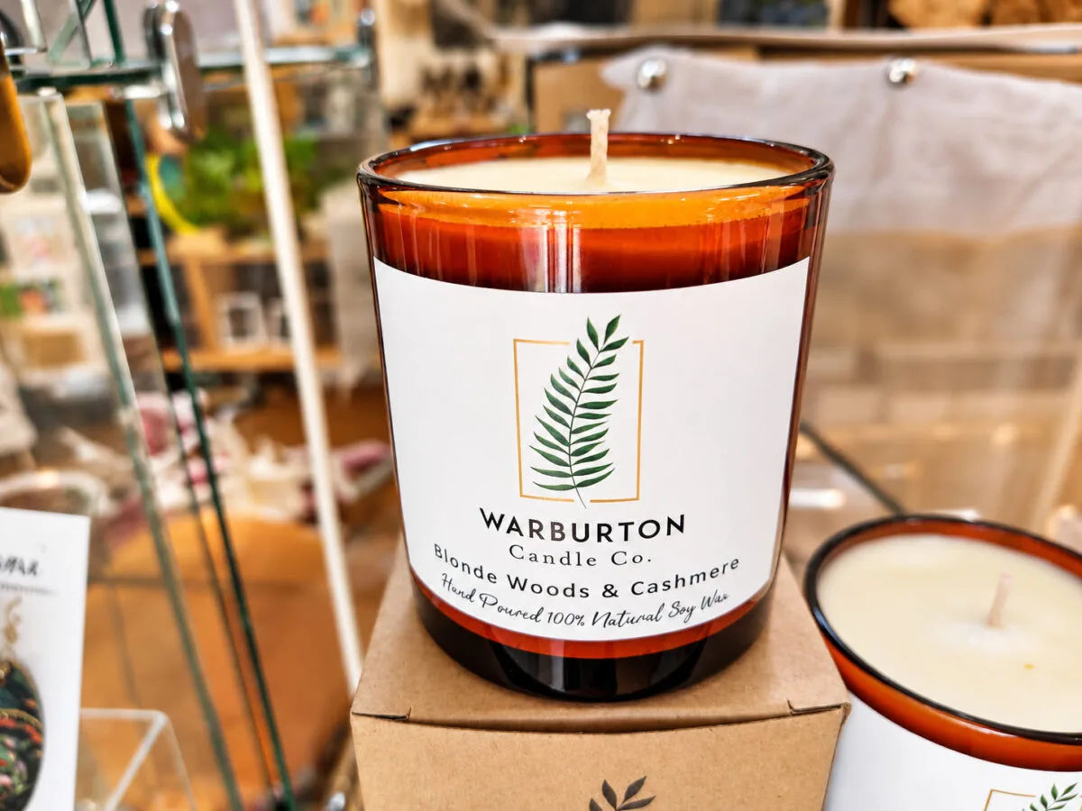 A Warburton Candle Co. soy candle in an amber jar on display in the Waterwheel shop